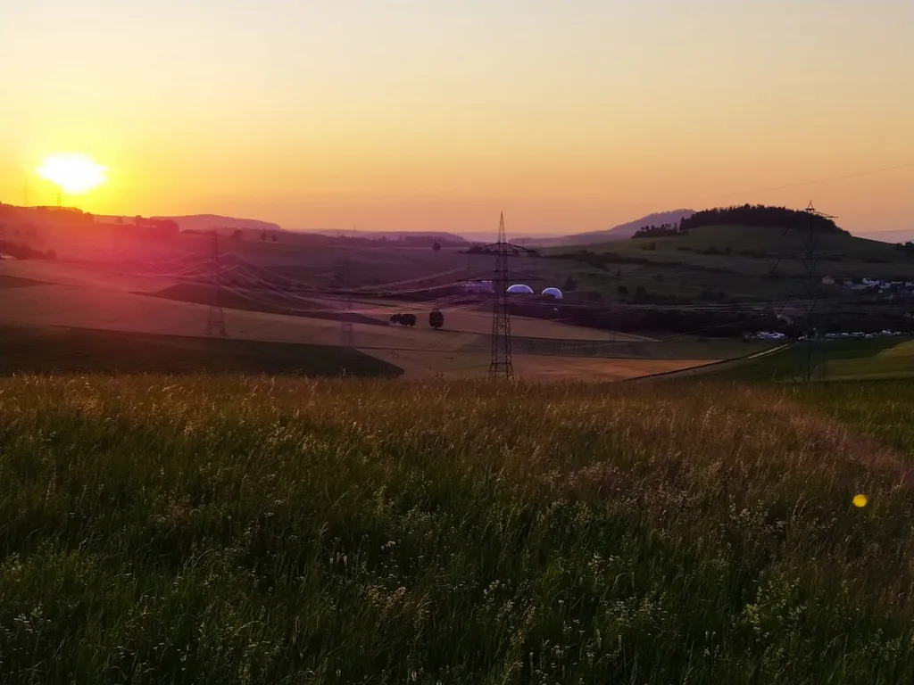 Idyllischer Sonnenaufgang vom Stellplatz aus mit Blick über Wiesen und Felder