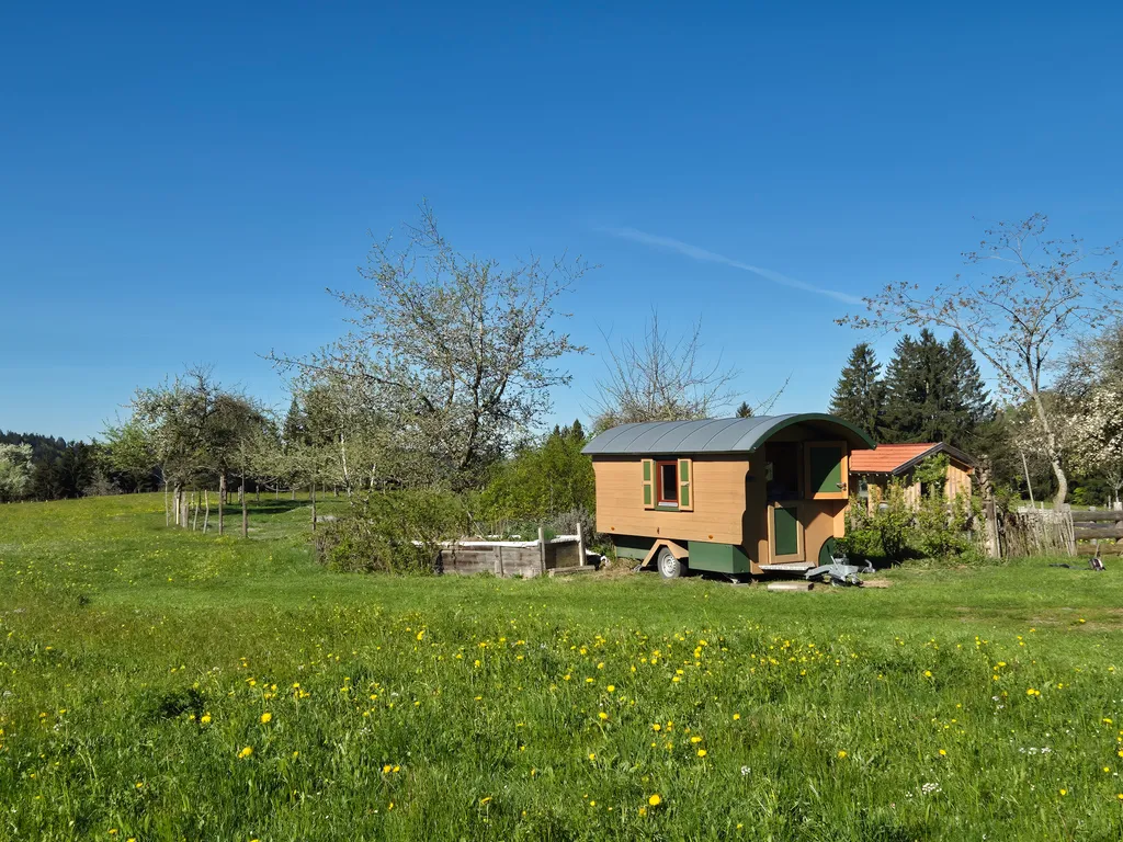 Schäferwagen mit Blick auf Weide und Bienenhaus.