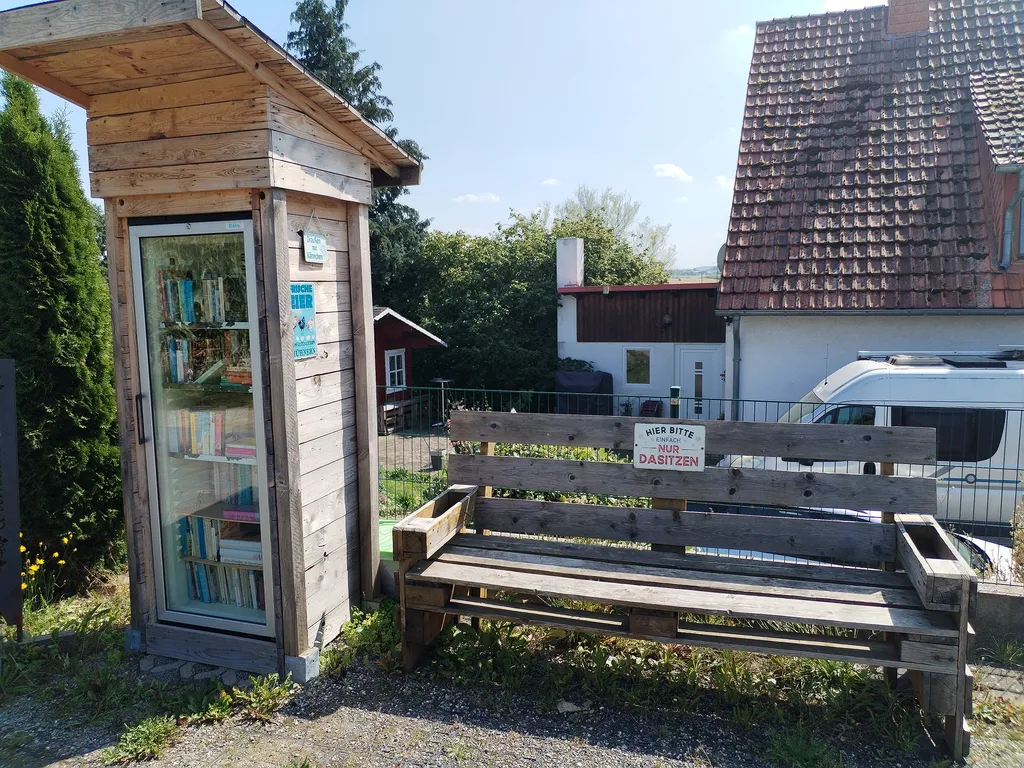 Bücherzelle mit Sitzbank vor dem Haus