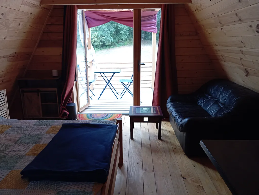 Vu depuis l'intérieur de la cabane , petite terrasse devant avec table et chaises.