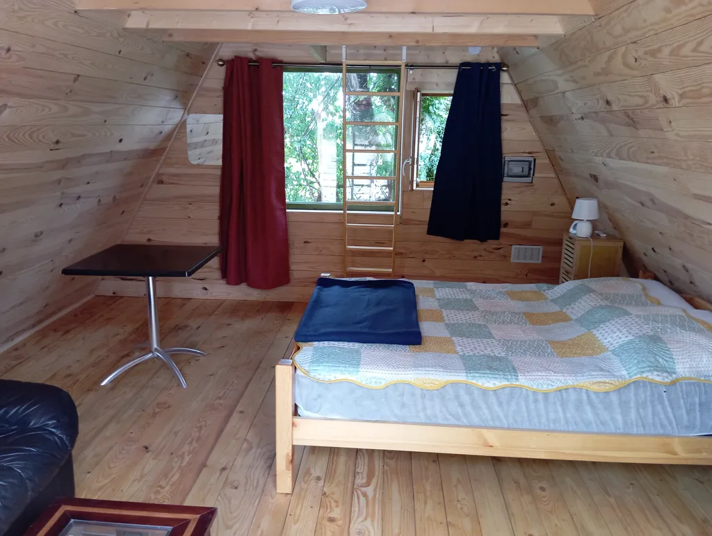 Chambre de 20 mètres carrés avec lit de 140 cm de large , banquette pour 2 personnes, une table et 2 chaises .