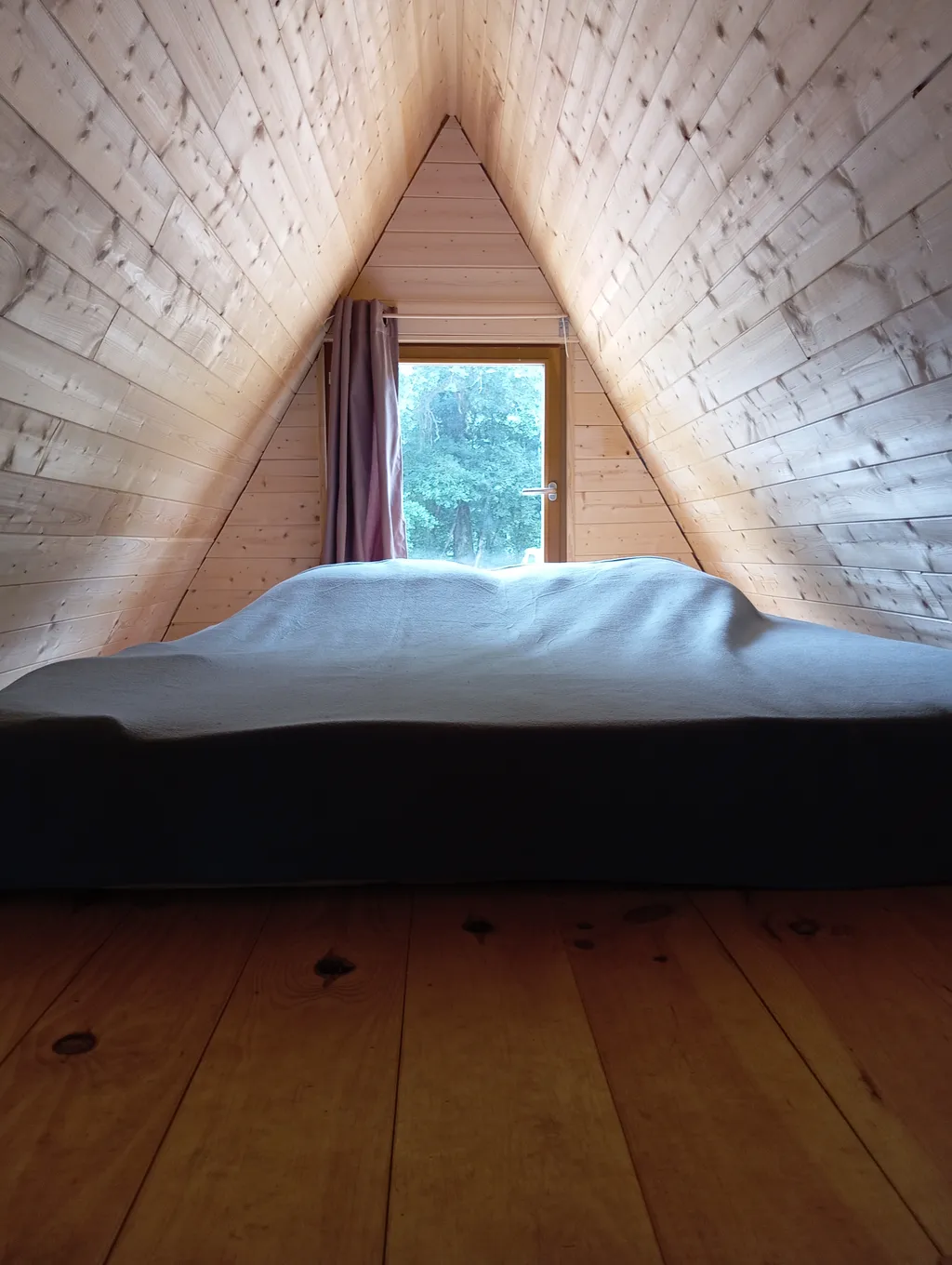 Photo de la mezzanine avec le matelas et la vue sur la nature .